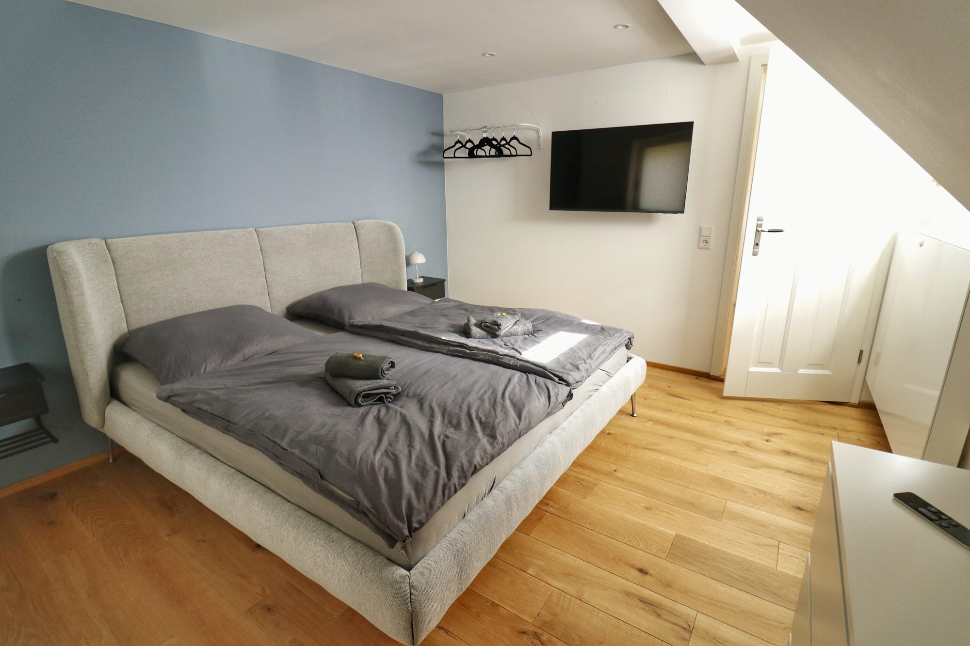 Schlafzimmer der Lodge mit Doppelbett, blauer Wand und Fernseher